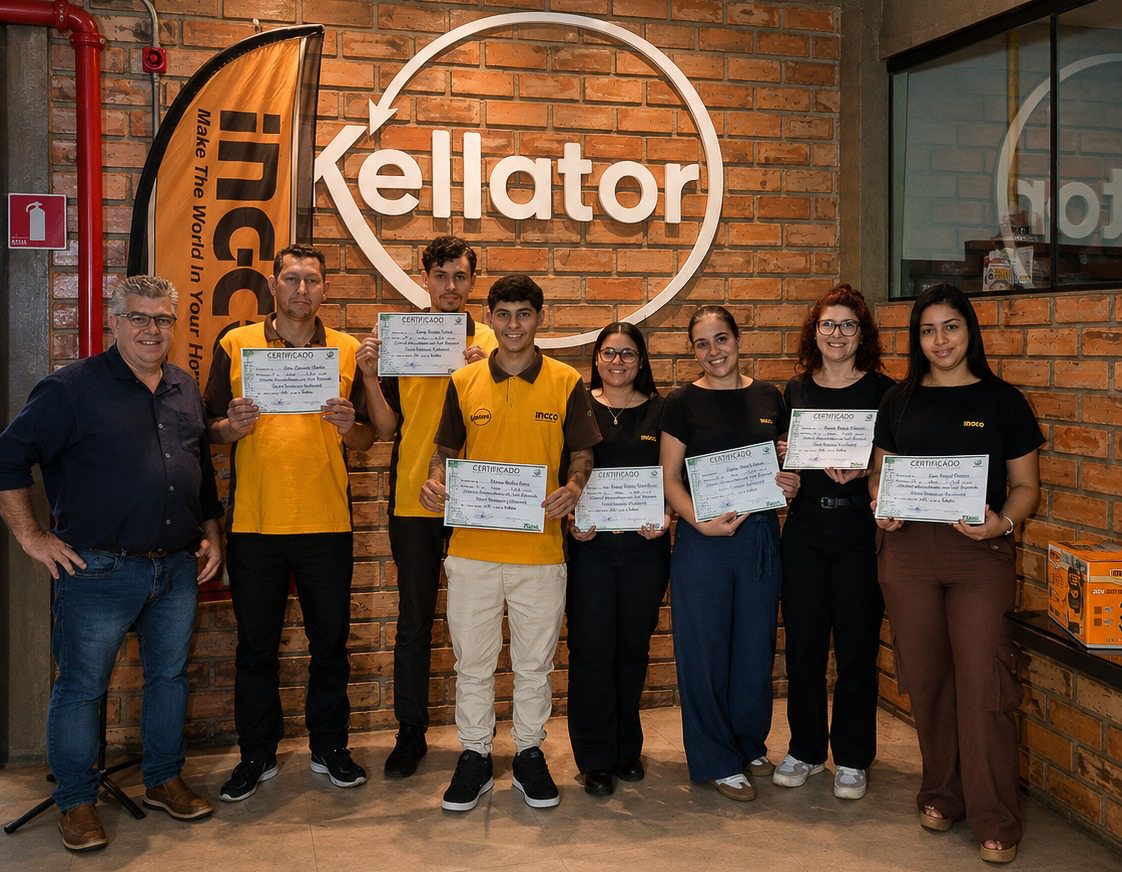 Colaboradores da Kellator com certificados de conclusão de curso, diante do letreiro da empresa