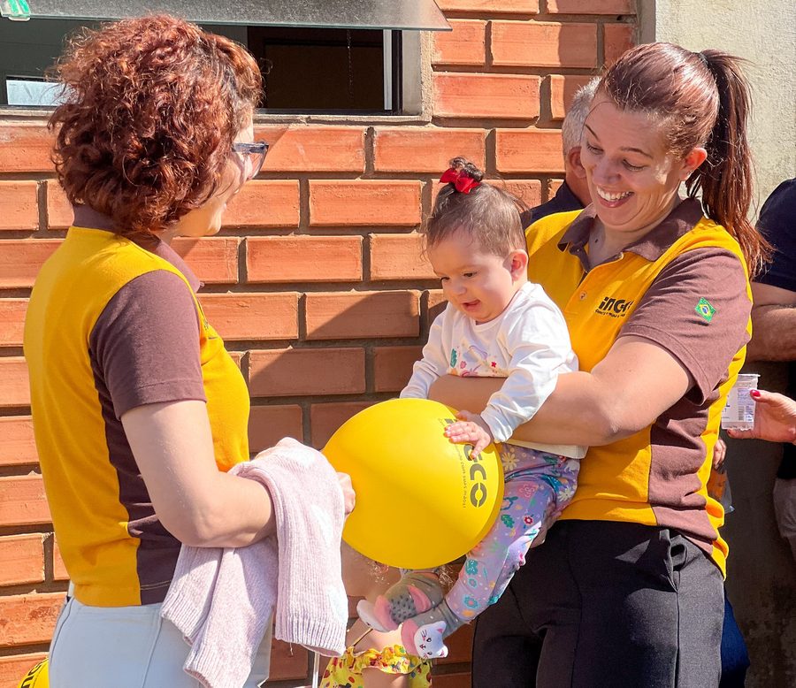 Colaboradoras da Kellator com uniforme INGCO brincando com uma criança em ação na comunidade