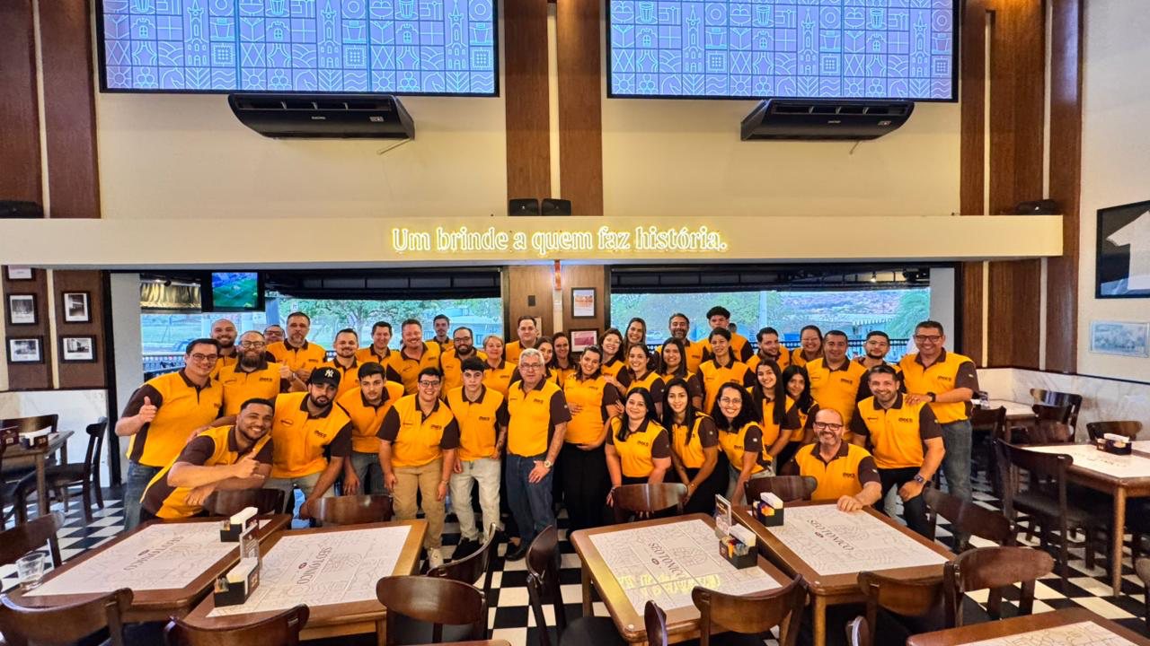 Equipe da Kellator reunida em confraternização, sob o letreiro Um brinde a quem faz história